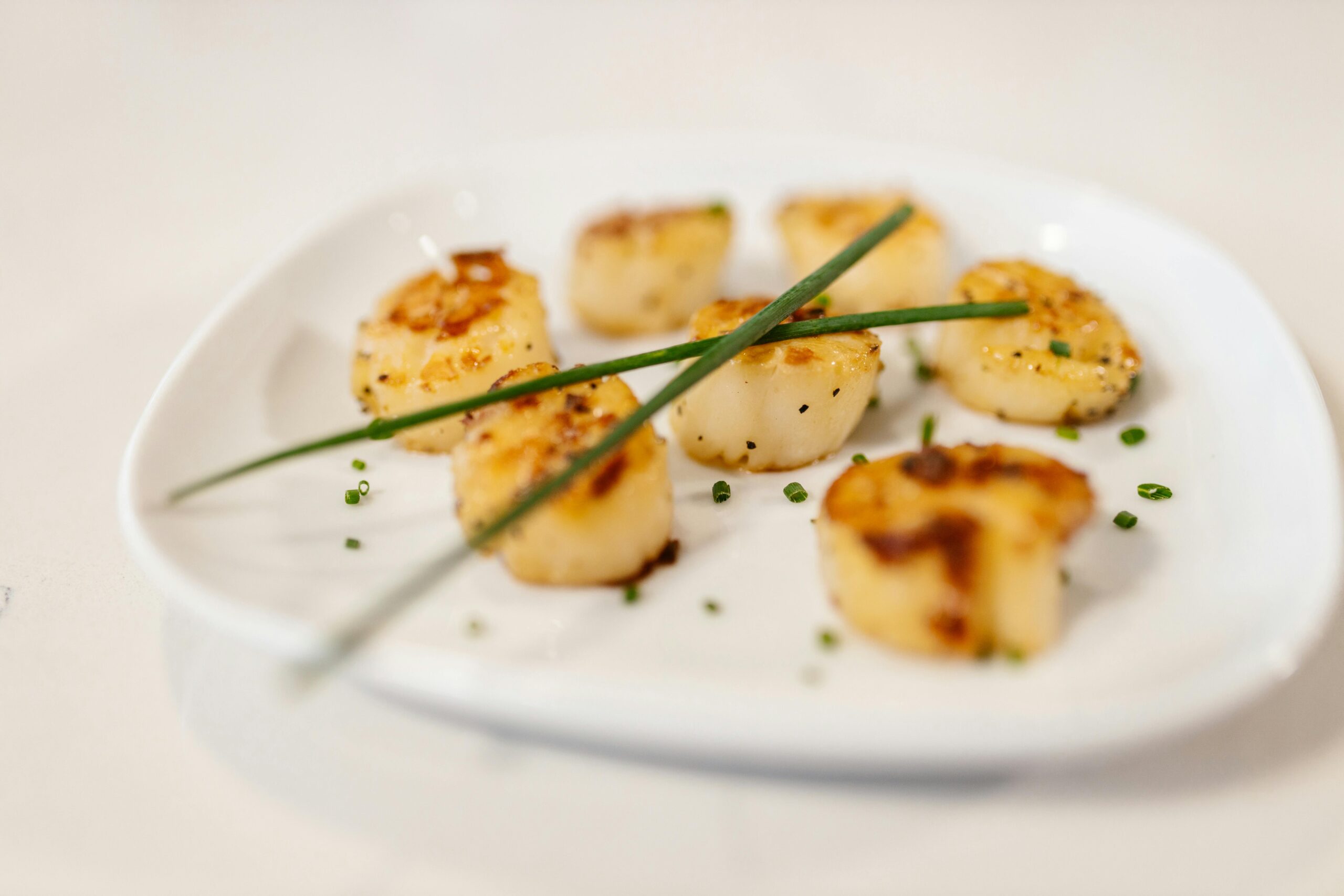 Crispy lion's mane mushroom "scallops" garnished with fresh parsley on a white plate.