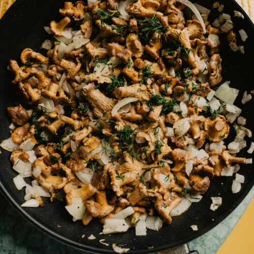 A skillet filled with sautéed wild mushroom medley with herbs and garlic.